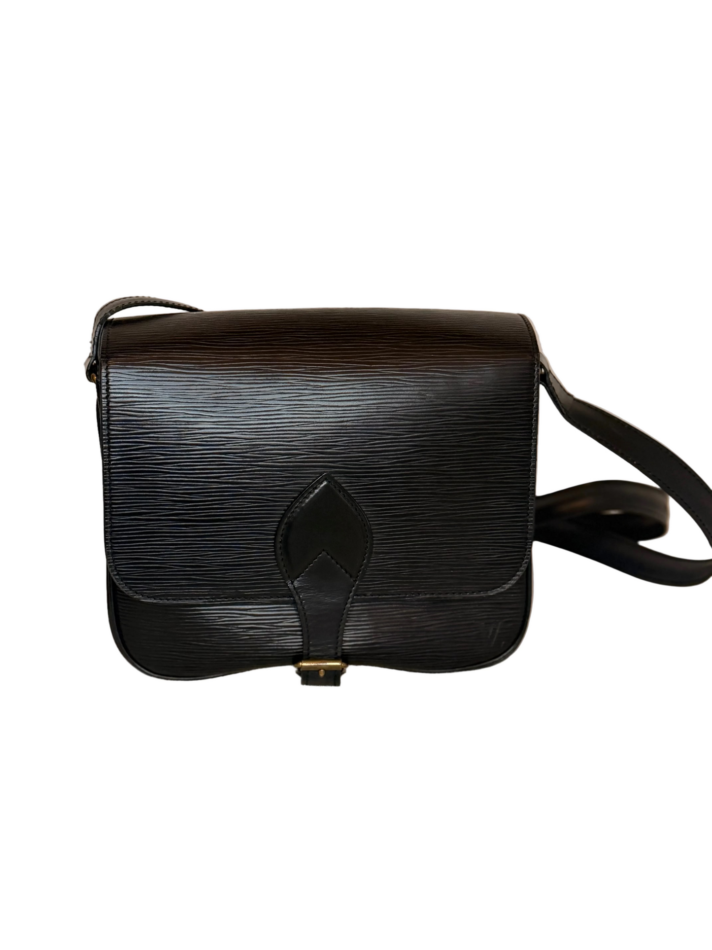 A black textured leather shoulder bag with a central strap detail and a small gold-tone buckle, resting on a light beige fabric surface against a plain beige background.
