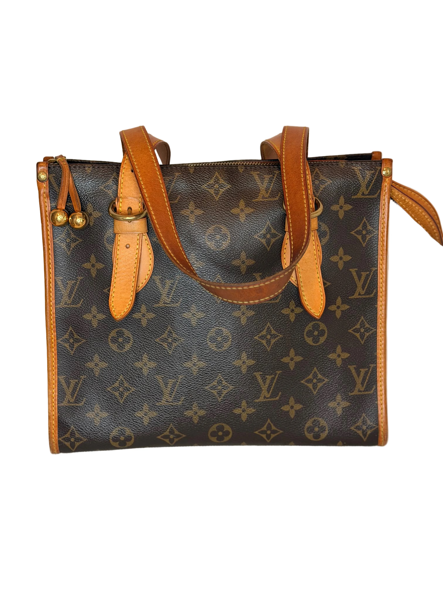 A Louis Vuitton monogram canvas shoulder bag with tan leather handles and trim, displayed on a light beige textured surface against a neutral beige background.